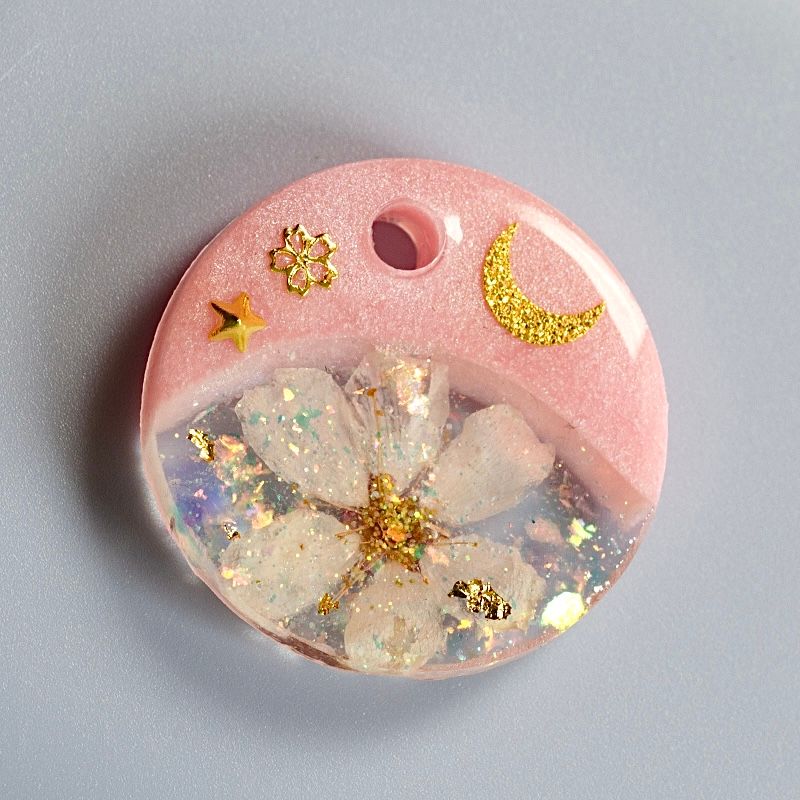 A picture of Hundemarke mit einer echten Kirschblüte und Glitzerakzenten. Mond und Sterne sowie feines Blattgold bringen einen zauberhaften Look. In rosa oder blau erhältlich und limitiert auf insgesamt vier Stück (jeweils eine Marke für Version A, B, C und D).