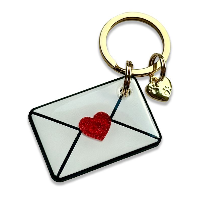 A picture of Hundemarke in Briefform. Verziert mit einem kleinen roten Glitzerherz. Auf die Rückseite kann ein kurzer Text geschrieben werden. Auf Wunsch kann auch die Vorderseite mit dem Namen deines Hundes beschriftet werden. Die Marke eignet sich auch als Schlüsselanhänger, wenn du noch nach einem Geschenk für eine liebe Person suchst.